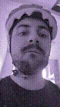 a selfie of a white person, wearing either headphones or a helmet, making an odd expression. the photo is edited to be colorized into a monochrome purple-ish color palette.